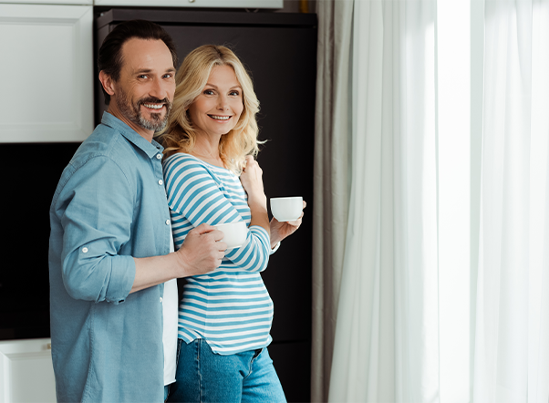 Smiling couple holding mugs in home interior